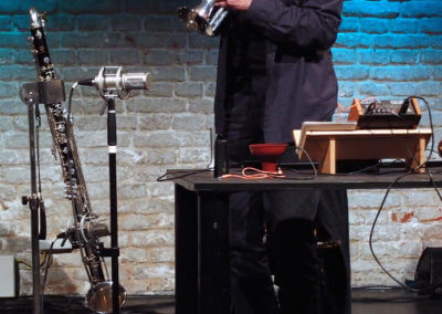 Udo Schindler bläst in ein Kornett, daneben eine Bassklarinette und ein Analog-Synthesizer